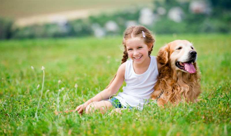 Girl and dog sitting on the grass outdoors